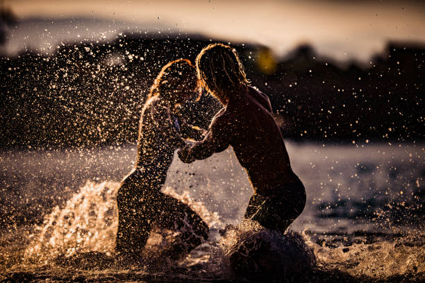istock Couple holding hands and having fun while spinning in the sea at sunset. 1051186766