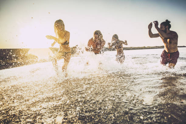 istock Playful couples having fun in the sea at sunrise. 1051189562