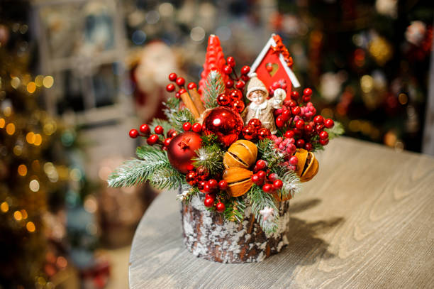 christmas table decoration made of stump decorated with berries, glass balls, dried orange peel and toys - christmas tree bead humor imagens e fotografias de stock