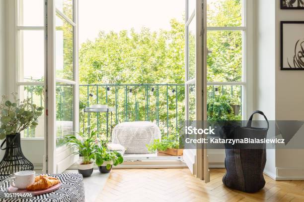 Open Glass Door From A Living Room Interior Into A City Garden On A Sunny Balcony With Green Plants And Comfy Furniture Stock Photo - Download Image Now
