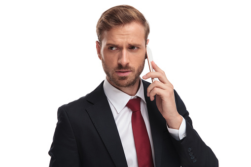 anxious businessman talking on the phone looks to side
