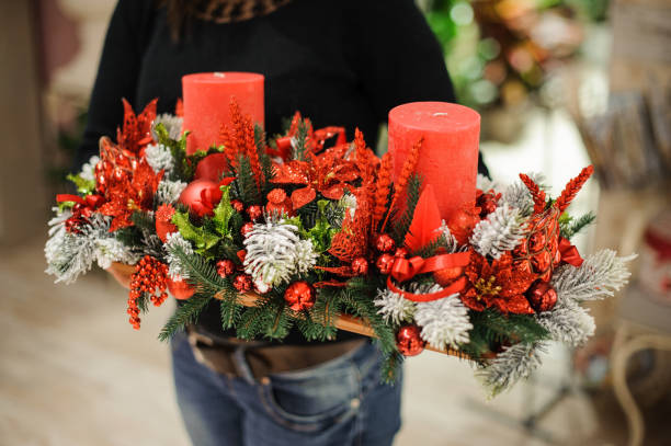 kobieta trzymająca ozdobny stół kompozycja świąteczna wykonana z jodły, czerwonych świec, kwiatów i kulek na drewnianej desce - poinsettia christmas candle table zdjęcia i obrazy z banku zdjęć