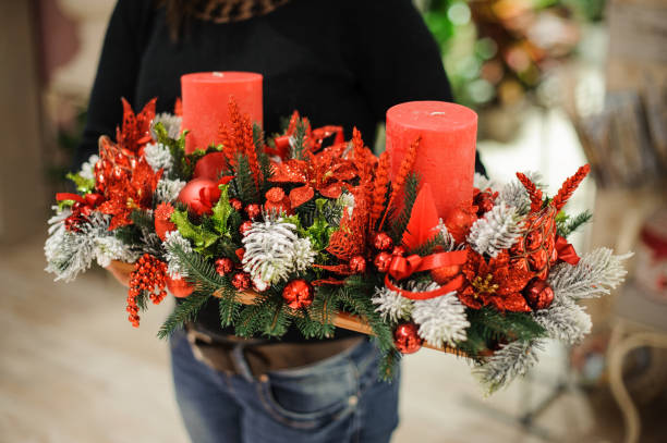 женщина, держащая декоративный стол рождественская композиция из елки, красные свечи, �цветы и шары на деревянной доске - poinsettia christmas candle table стоковые фото и изображения