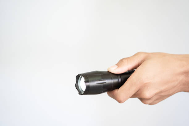 фонарик под рукой, держащийся на белом фоне - black flashlight light bulb electricity стоковые фото и изображения