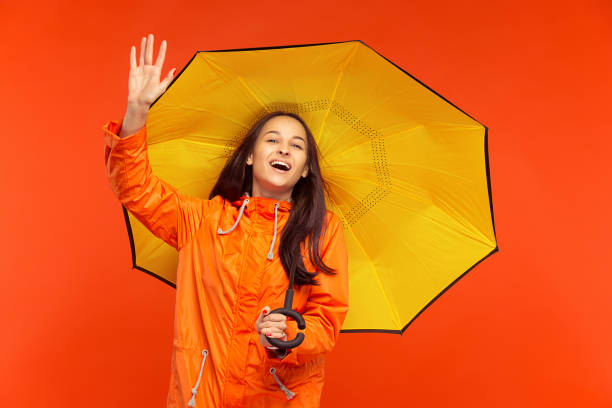 istock The young girl posing at studio in autumn jacket isolated on red 1051211712
