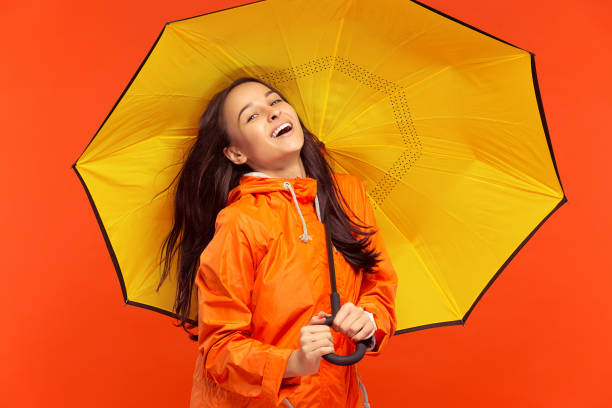 istock The young girl posing at studio in autumn jacket isolated on red 1051211718