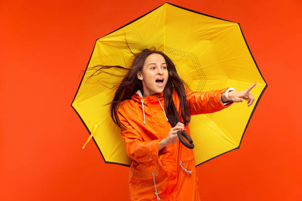 istock The young girl posing at studio in autumn jacket isolated on red 1051211728