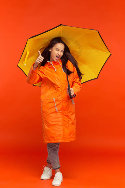 istock The young girl posing at studio in autumn jacket isolated on red 1051211736