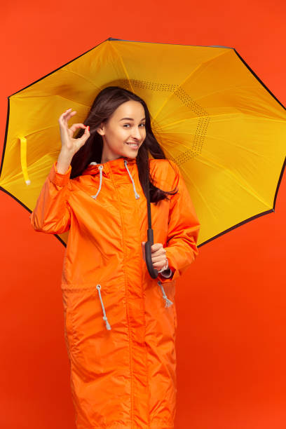 istock The young girl posing at studio in autumn jacket isolated on red 1051211746
