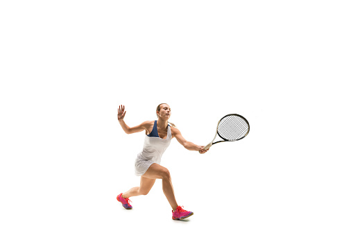 Adult woman playing tennis. Studio shot of fit young girl isolated on white background in motion or movement during sport game..