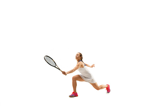 Adult woman playing tennis. Studio shot of fit young girl isolated on white background in motion or movement during sport game..