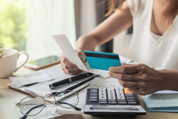 jeune femme vérification de solde de compte bancaire, les impôts, les factures et calculer les frais de carte de crédit à la maison - endettement photos et images de collection