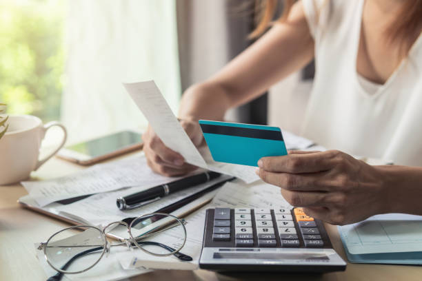 Young woman checking bills, taxes, bank account balance and calculating credit card expenses at home stock photo