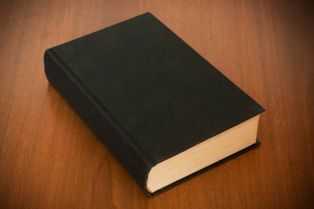 Blank old black book on wooden table ready for mockup or cover customization