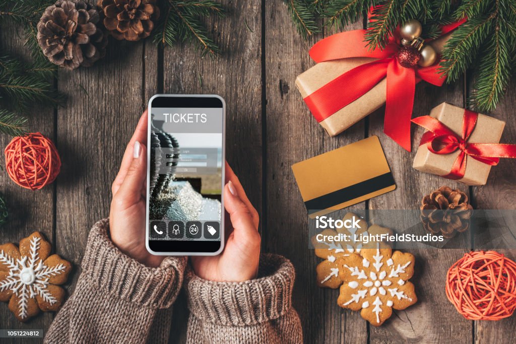 verkürzten Blick auf Frau mit Smartphone mit Ticket-app auf hölzernen Hintergrund mit Kreditkarte und Weihnachtsgeschenke - Lizenzfrei Weihnachten Stock-Foto