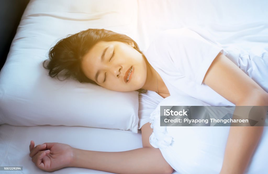 Women sleeping on the bed and grinding teeth,Female tiredness and stress Female sleeping on the bed and grinding teeth,Female tiredness and stress Bruxism Stock Photo