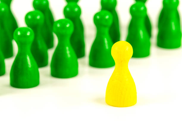 Group of wooden people figurines. Green man stands out from group, Crowd, meeting, social activity. Society, social group. Herd instinct, management of people. Human resources, workers stand together.