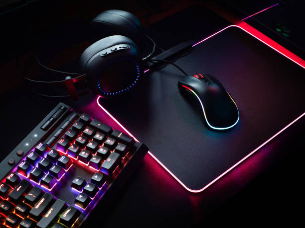 gamer workspace concept, top view a gaming gear, mouse, keyboard with RGB Color, joystick, headset, webcam, VR Headset on black table background. stock photo