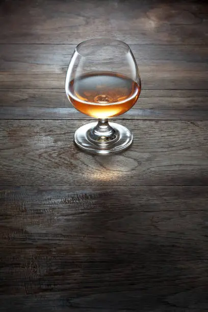 view of glass of  cognac on brown color wooden table surface