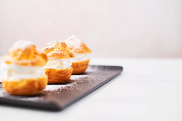 istock Delicious profiteroles with cream and powdered sugar on a plate. 1051258740