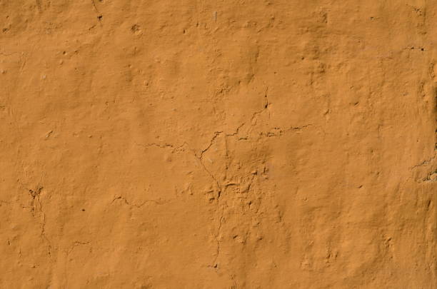 Painted adobe wall Fragment of the rough textured adobe wall painted in brown, orange color adobe material stock pictures, royalty-free photos & images