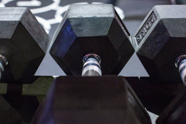 istock Black rubber dumbbells. Hexagonal heavy duty weight set used for serious hardcore gym workouts, exercise training and workout routines 1051262982