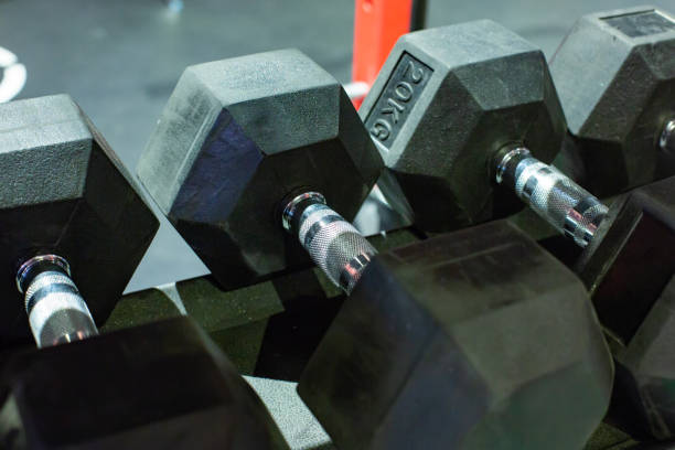 istock Black rubber dumbbells. Hexagonal heavy duty weight set used for serious hardcore gym workouts, exercise training and workout routines 1051263012