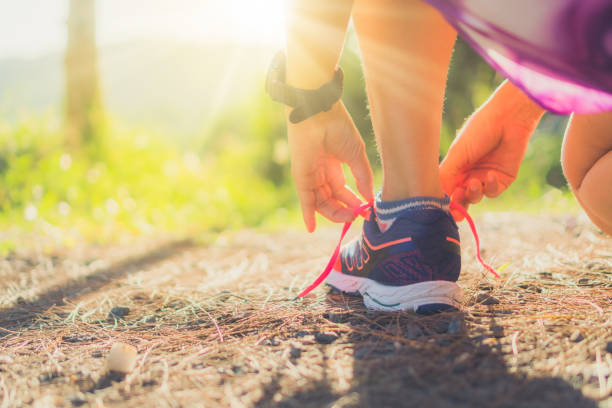 kobieta nosi buty do biegania na chodzenie i bieganie na zielonym tle natury. koncepcja ćwiczeń zdrowotnych. - shoe tying adult jogging zdj�ęcia i obrazy z banku zdjęć