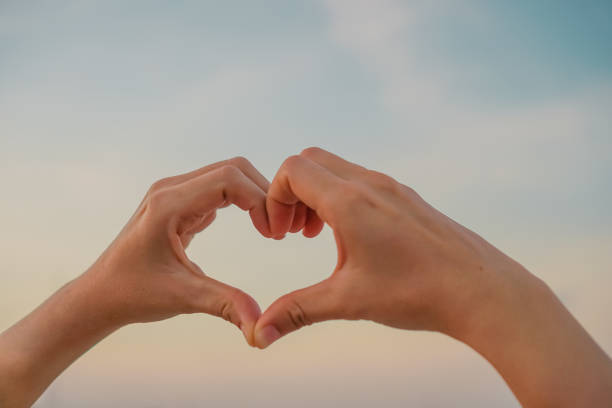 istock Woman hand do heart shape on nature blue sky background. 1051263734
