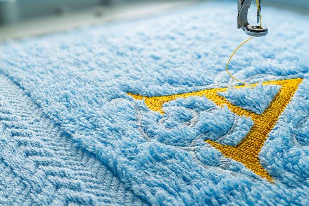 Embroidery machine and alphabet design on towel Close up picture embroidery design yellow alphabet monogram on blue towel embroider by machine, copy space on the left side. embroidery photos stock pictures, royalty-free photos & images