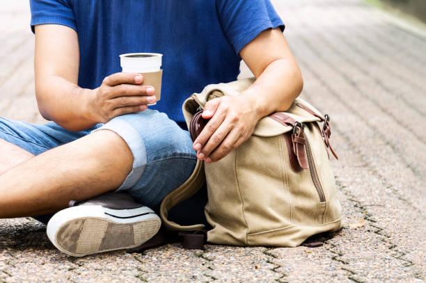 istock People man holding coffee cup or disposable cup with a black plastic cap and backpack sitting in the garden green nature background. Concept happy man with leisure and drink coffee. 1051281476