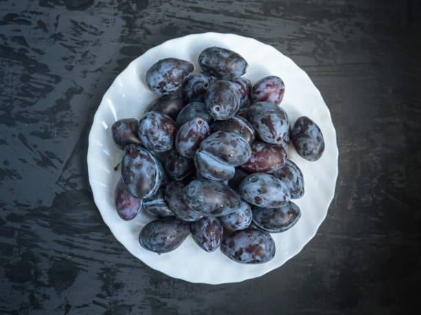 istock white plate with ripe prunes on a dark wooden background 1051283650