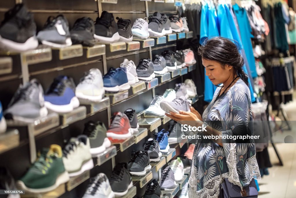 Woman choosing sport shoes Woman choosing sport shoes in department store Sports Shoe Stock Photo