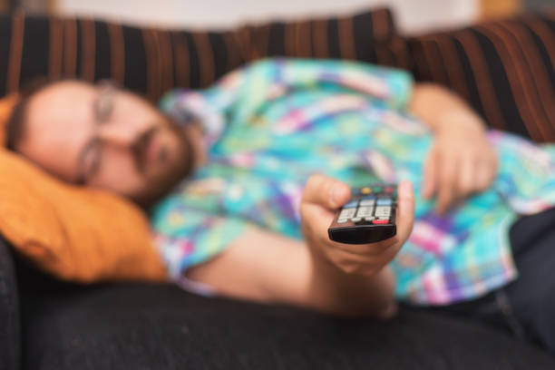 istock Man relaxing in sofa with remote control watching tv. Shallow dof focus on remote control. 1051284034