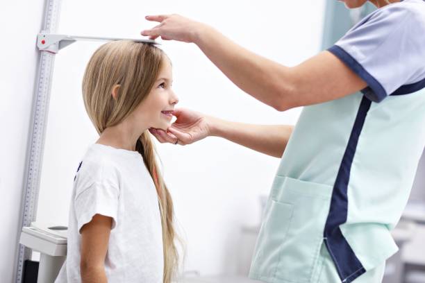 Female doctor measuring height of girl in clinic Picture of female doctor measuring height of girl in clinic short length stock pictures, royalty-free photos & images