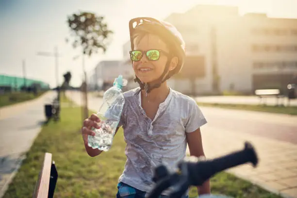 Photo of Little boy riding bicycle and drinking water