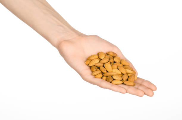 istock Nuts and cooking theme: man's hand holds nuts almonds on a white isolated background in studio 1051332542