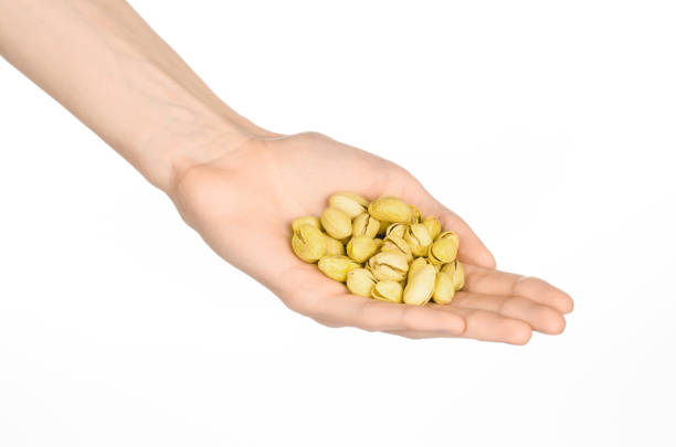 istock Nuts and cooking theme: man's hand holds nuts pistachios isolated on a white background in studio 1051333532