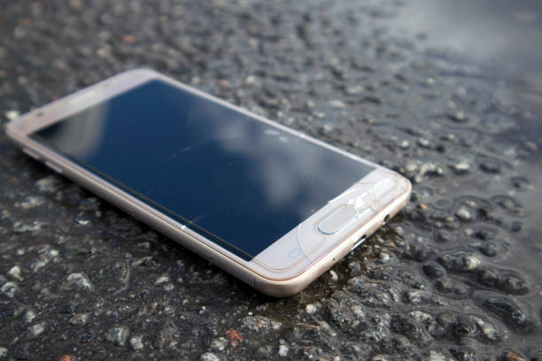 istock Modern smart phone with cracked screen glass lying in a puddle 1051338574