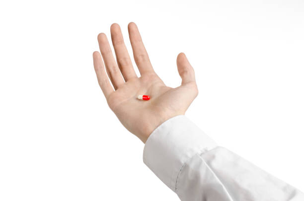 istock Medical theme: doctor's hand holding a red capsule for health on a white background isolated 1051342642