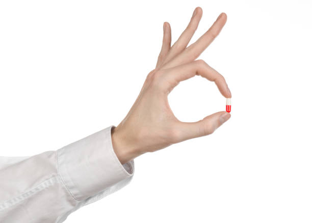 istock Medical theme: doctor's hand holding a red capsule for health on a white background isolated 1051343032