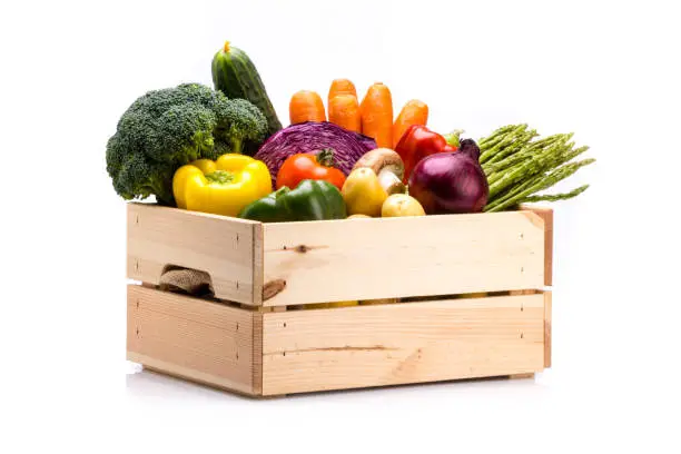 Photo of Pine box full of colorful fresh vegetables on a white background