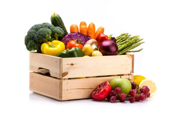 Photo of Pine box full of colorful fresh vegetables and fruits on a white background