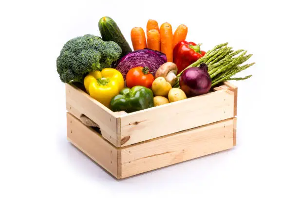 Photo of Pine box full of colorful fresh vegetables on a white background