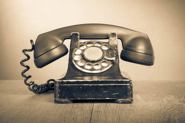 Old retro aged rotary telephone on wooden table. Vintage style sepia photo stock photo