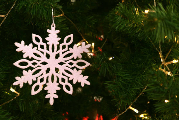istock White snowflake ornament hanging on sparkling Christmas tree 1051351690