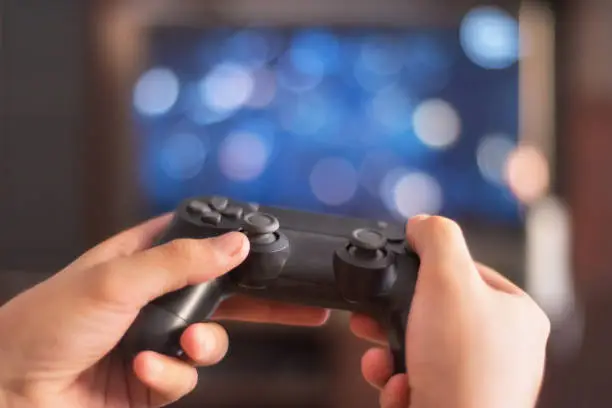 Man hold game pad in front of tv screen