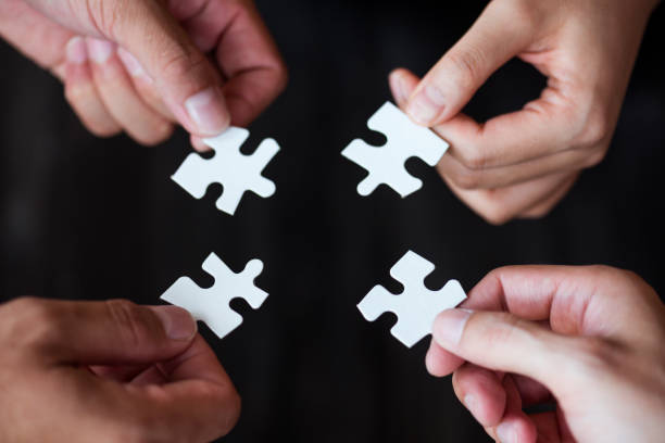 istock Cropped Image Of People Holding Jigsaw Puzzle Pieces Over Black Background 1051355498