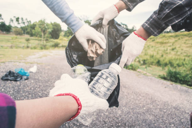istock Midsection Of People Wearing Glove While Collecting Garbage On Road 1051357602