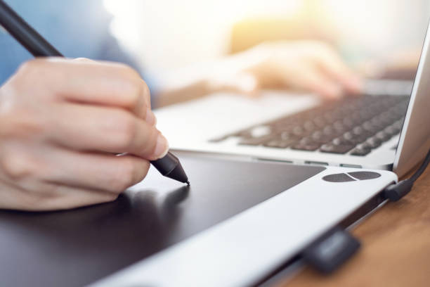istock Graphic designer using a stylus pen tablets, Photographer drawing and retouching image in laptop computer on desk 1051363898
